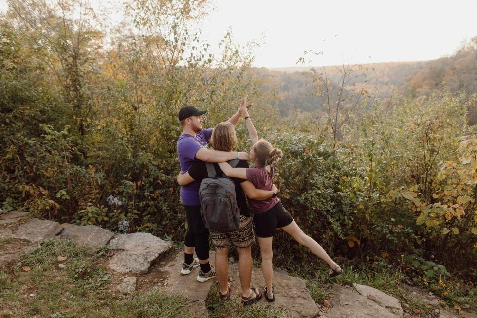 徒步旅行俯瞰森林景观的学生们拥抱并击掌