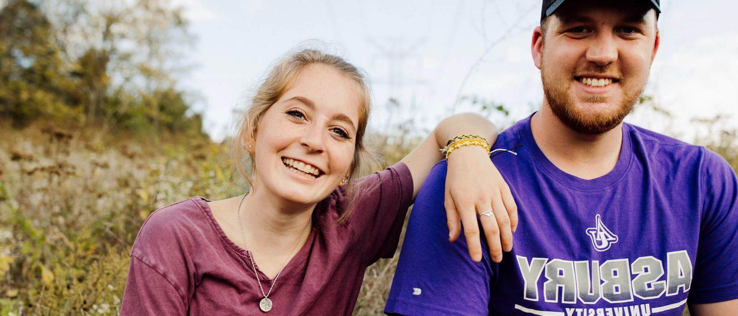两个阿斯伯里的学生坐在田野里微笑着拍照