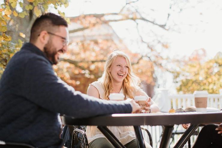 博彩app推荐(艾斯拜瑞大学市)的三名学生，其中两名可以看到，围坐在户外的一张桌子旁喝咖啡